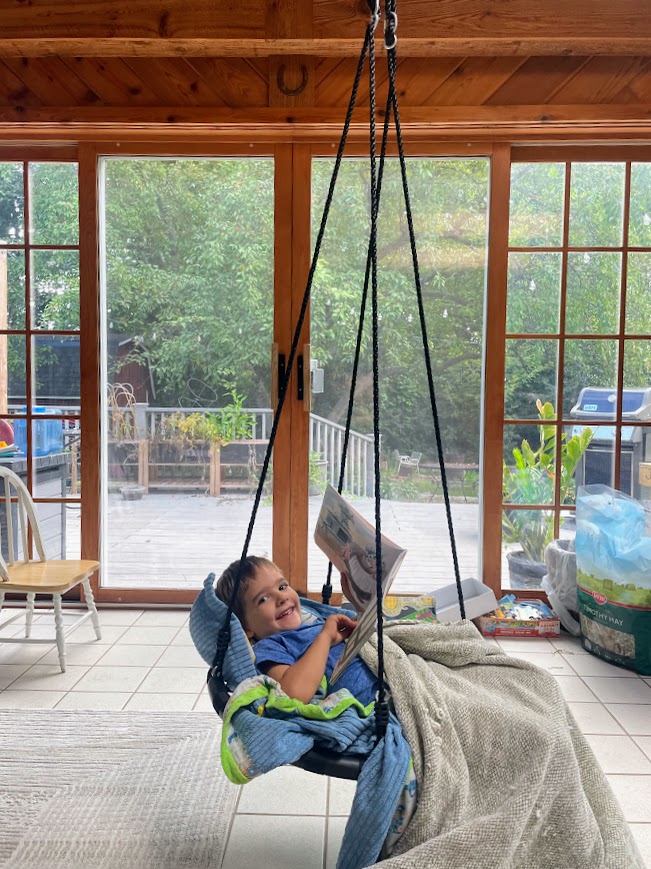 homeschool boy on an indoor swing reading a book