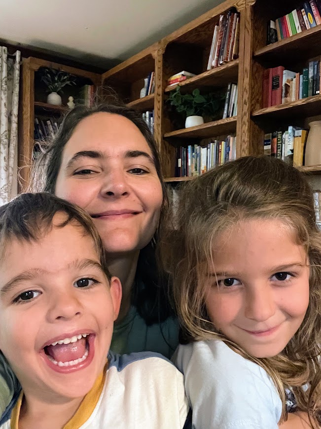 homeschool mom with two homeschool kids in front of bookshelves